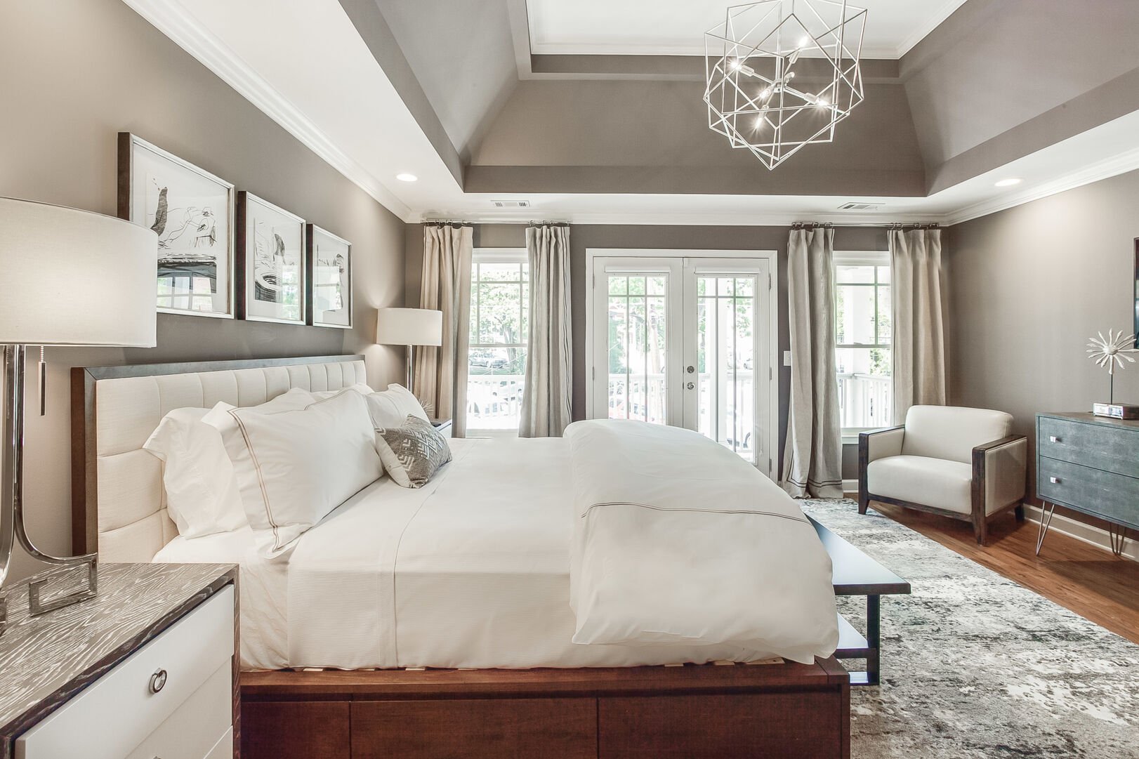 Large Bed, Arm Chair, Nightstands, Lamps, Dresser, and Window Doors to the Balcony.