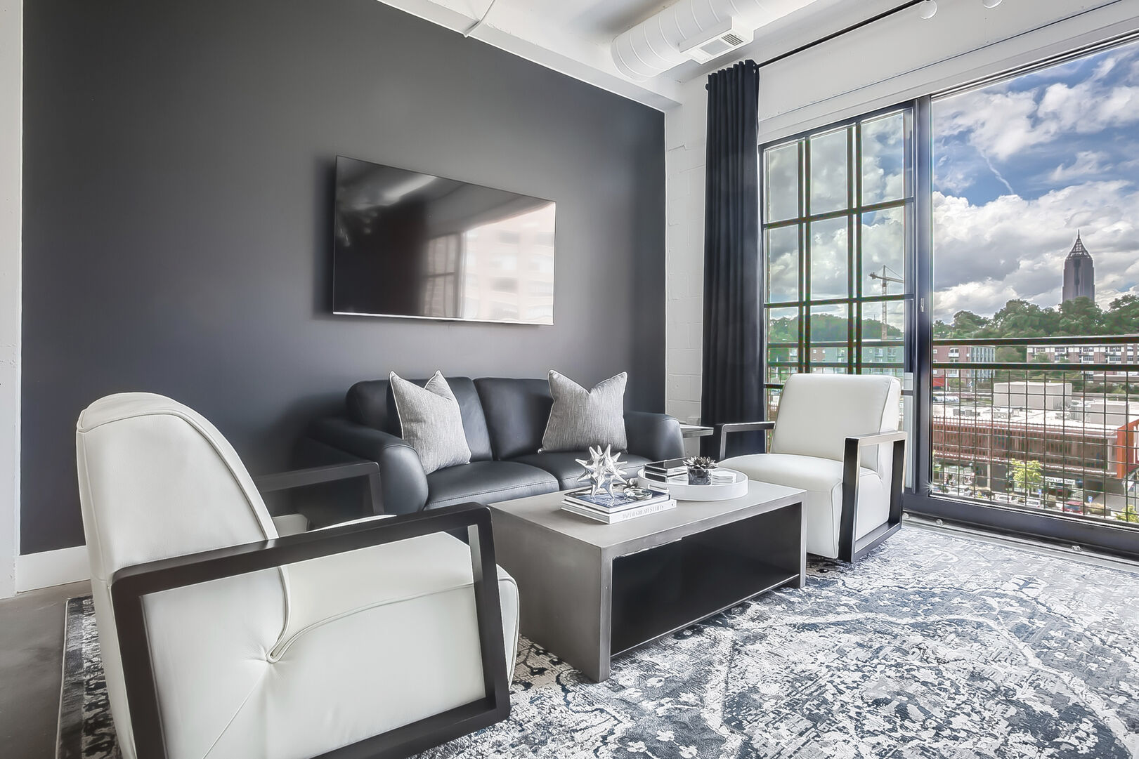 Living area with wall-mounted TV, sofa, two armchairs, and coffee table.