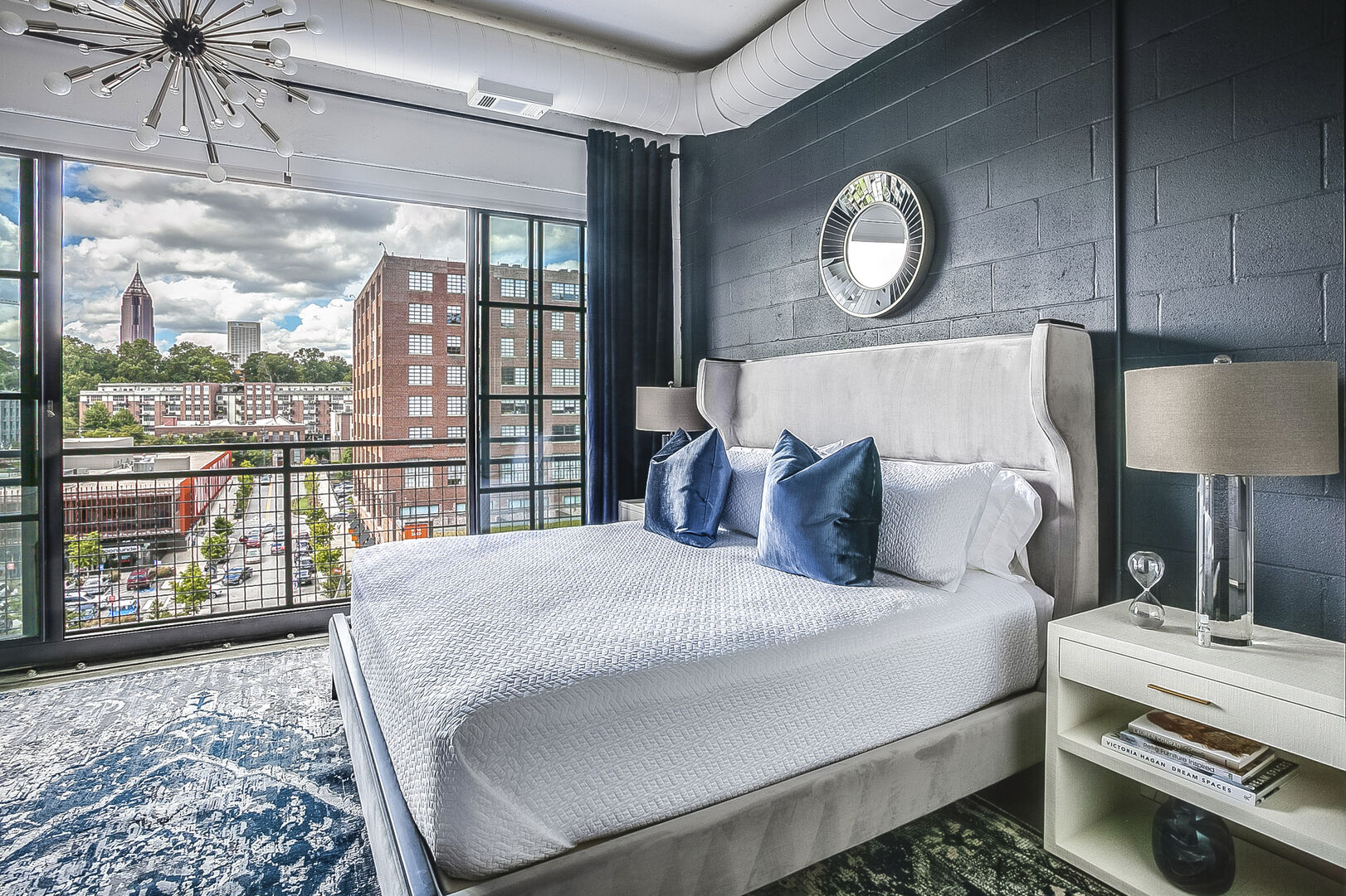 Sleeping area with a large bed, two nightstands, and an open window overlooking the city.