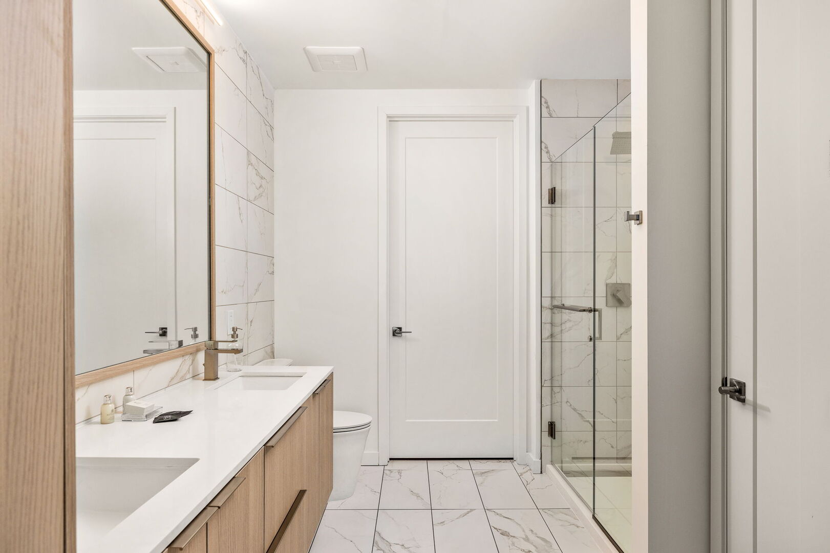 An en-suite bathroom featuring a double vanity and a spacious walk-in shower