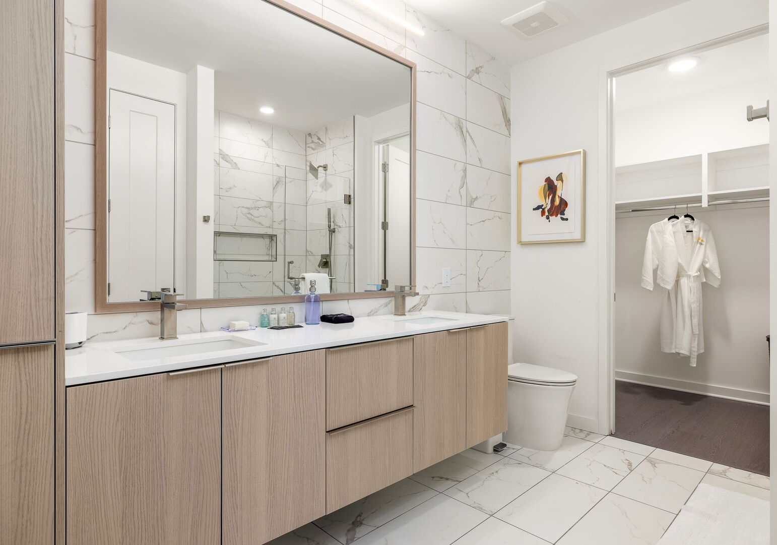 An en-suite bathroom featuring a double vanity and a spacious walk-in shower and closet