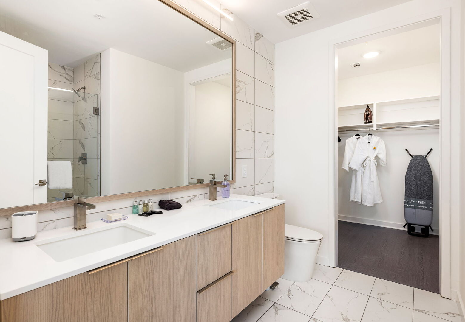 An en-suite bathroom featuring a double vanity and a spacious walk-in shower and closet