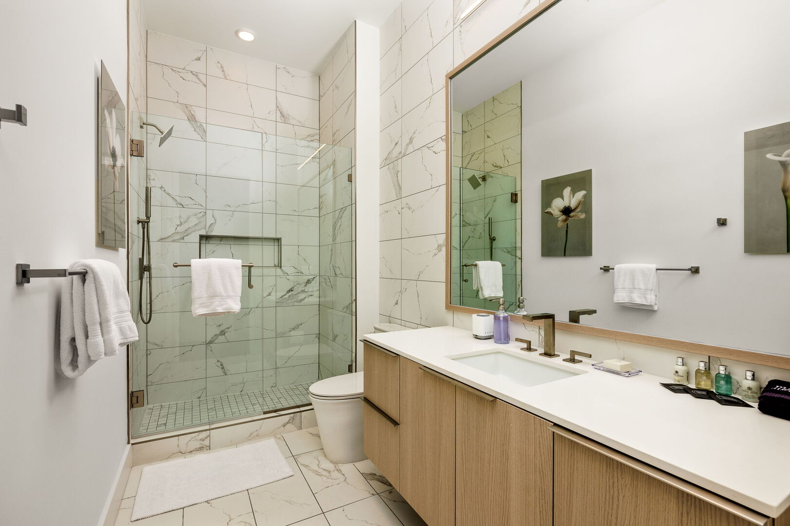 An en-suite bathroom featuring a single vanity and a spacious walk-in shower and closet