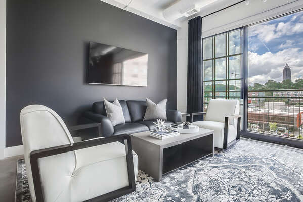 Living area with wall-mounted TV, sofa, two armchairs, and coffee table.