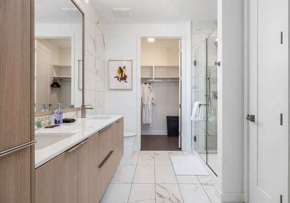 An en-suite bathroom featuring a double vanity and a spacious walk-in shower and closet