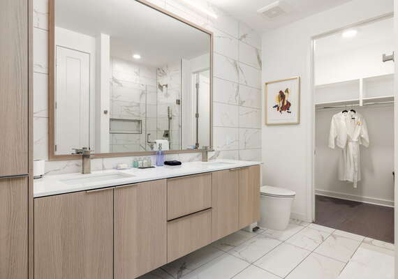 An en-suite bathroom featuring a double vanity and a spacious walk-in shower and closet