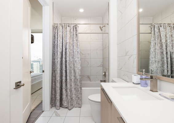 An en-suite bathroom featuring a single vanity and a spacious tub and shower.