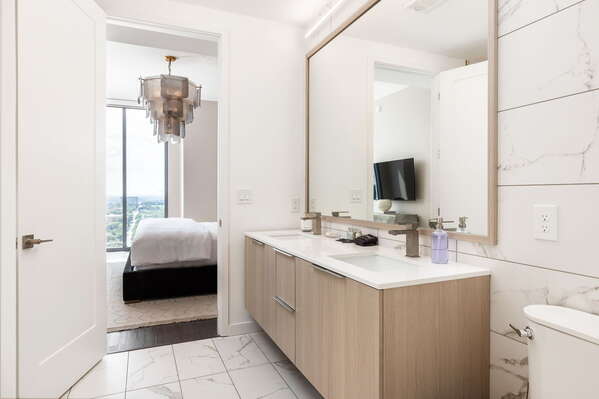 An en-suite bathroom featuring a double vanity and a spacious walk-in shower and closet
