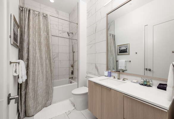 An en-suite bathroom featuring a single vanity and a spacious tub and shower.